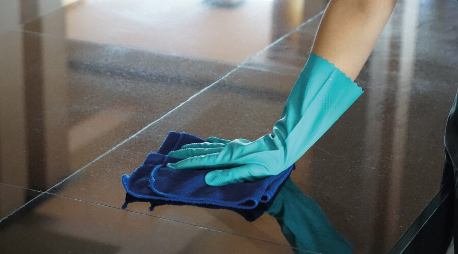 Mão de uma pessoa utilizando luva de proteção para limpeza de ambiente.