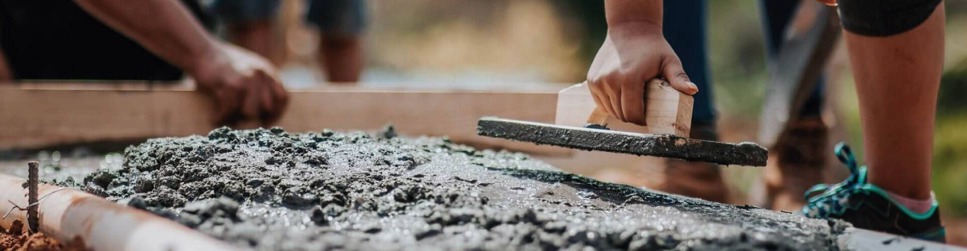 Profissional de obra cobrindo armadura com concreto.