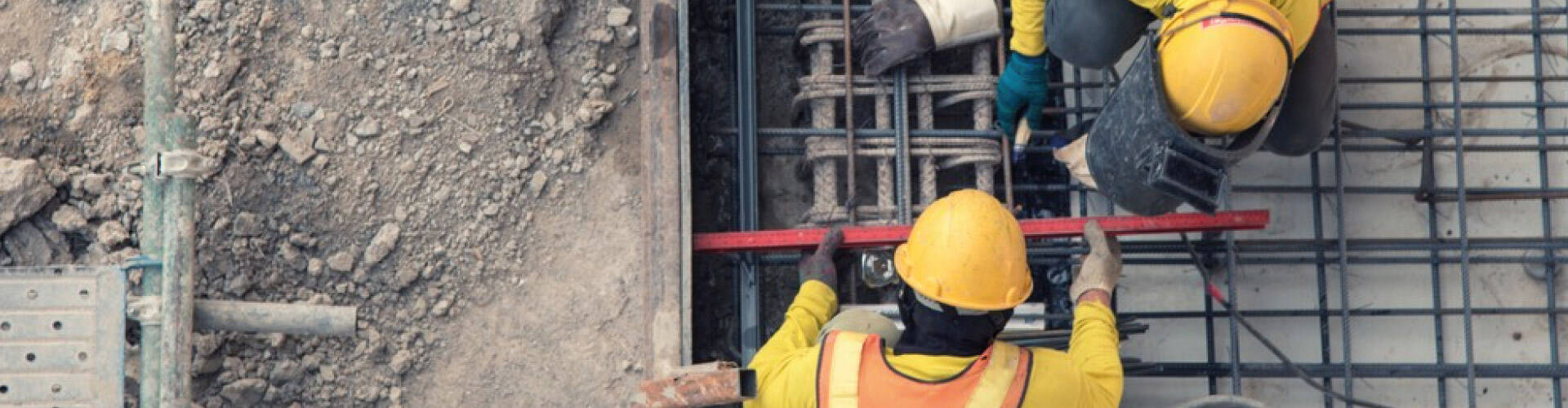 Dois homens medindo e instalando ferragens em uma obra.