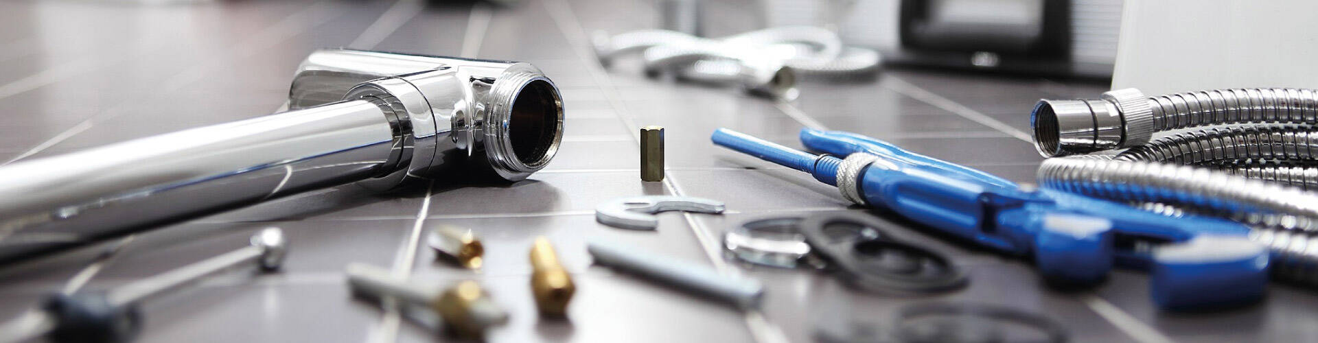 Encanador realizando instalação hidráulica com vários canos no chão.