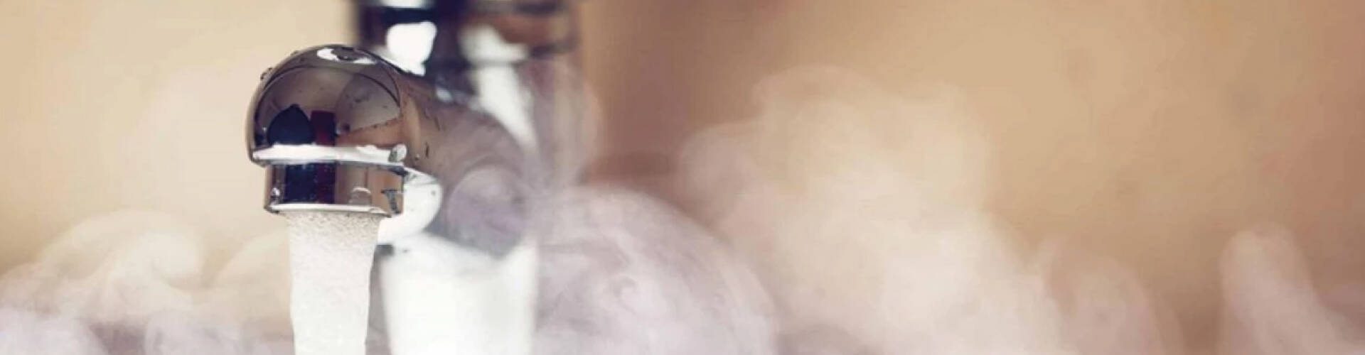 Torneira liberando água quente, com vapor ao redor.