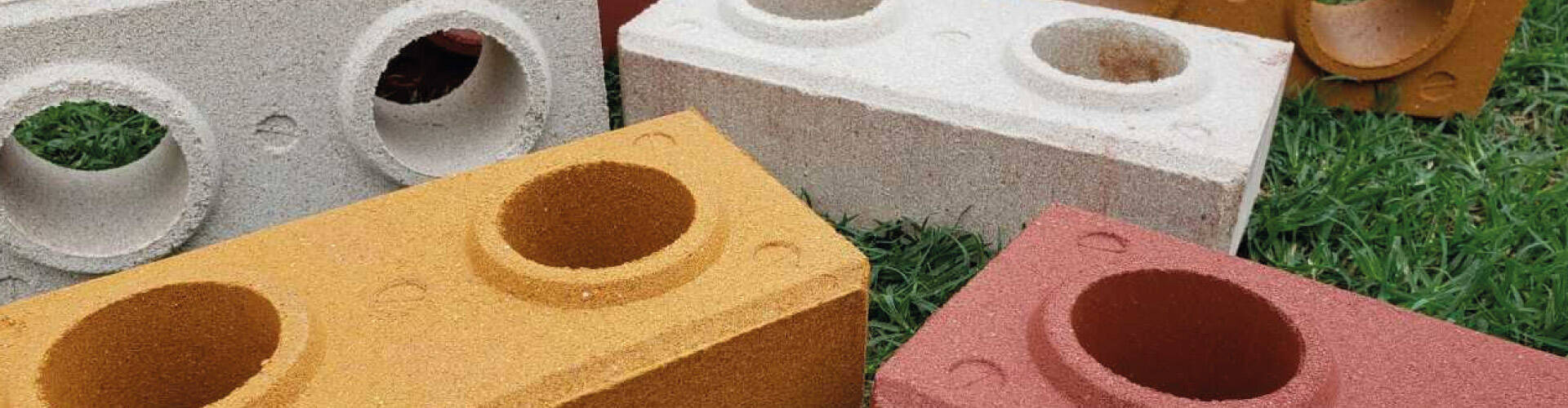 Tijolos ecológicos de várias as cores numa grama verde.